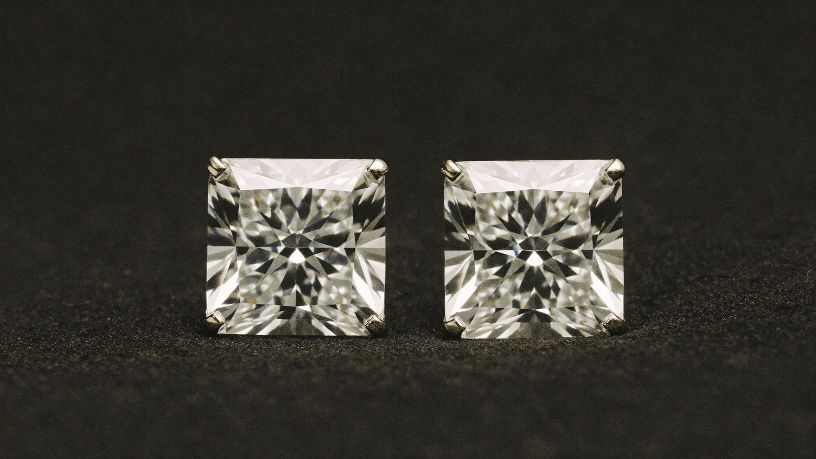 Two round brilliant diamonds side by side on dark fabric
